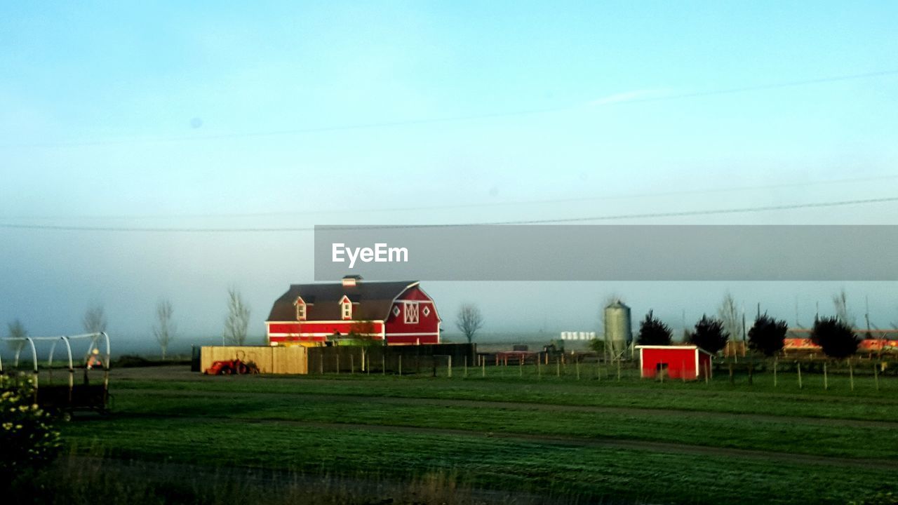 Silo and built structures on rural landscape against clear sky