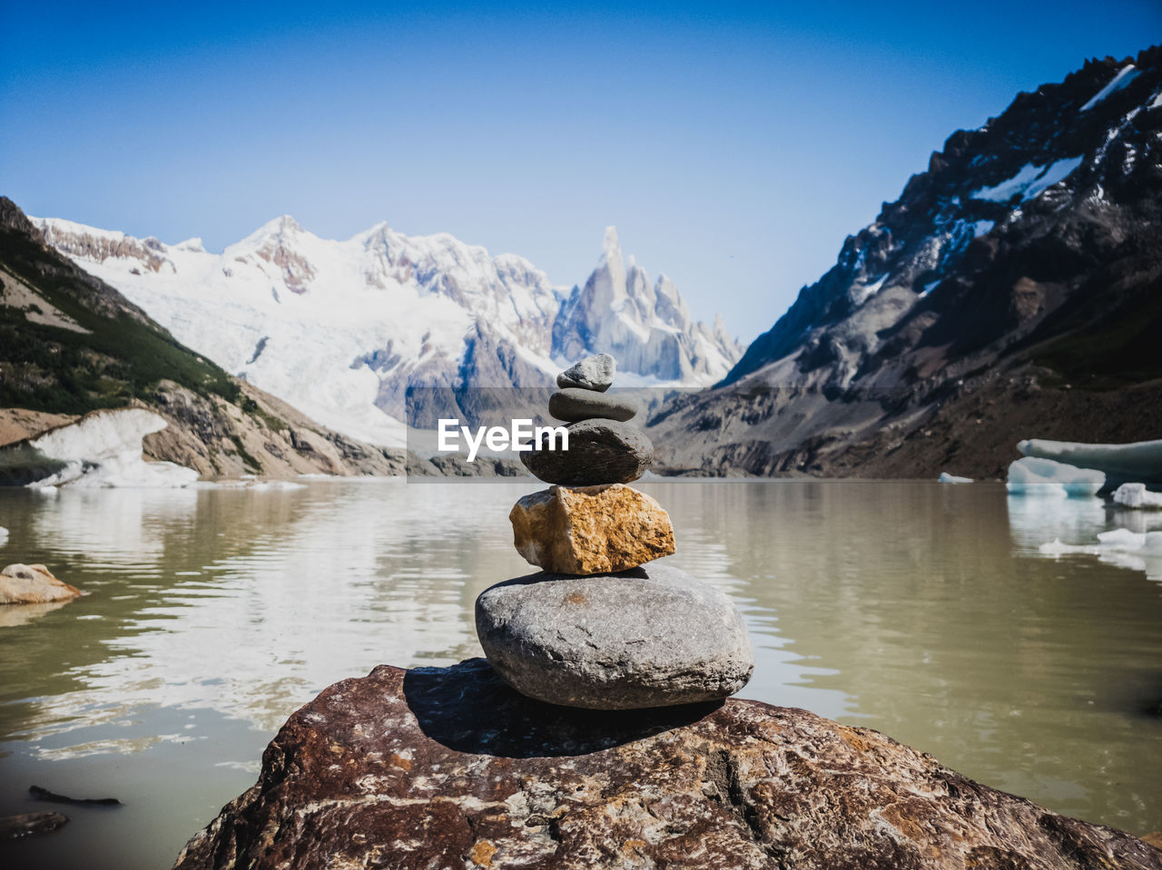 Stack of rocks by lake against sky