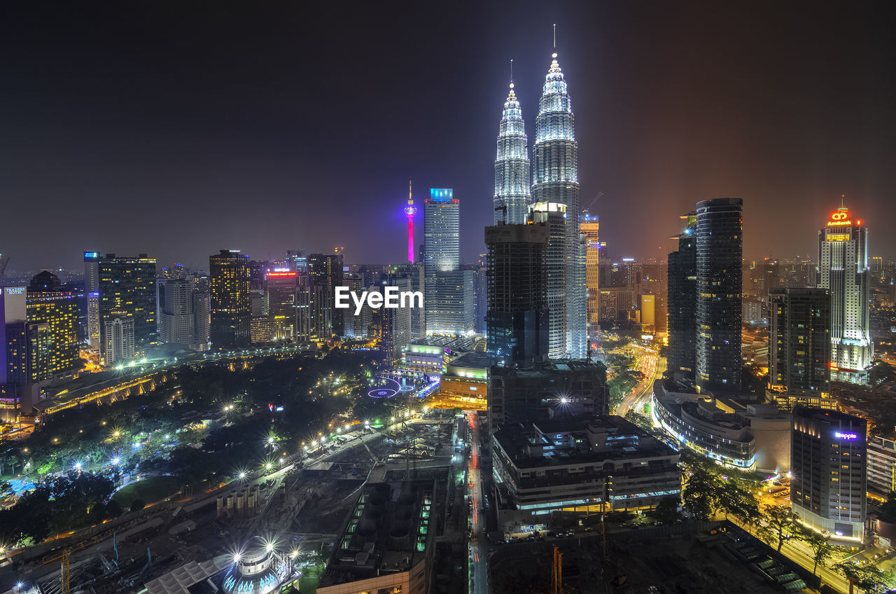 Illuminated petronas towers and city against clear sky at night