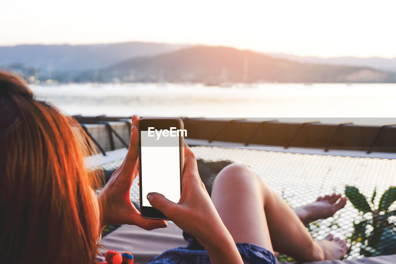 Woman using mobile phone while sitting on lounge chair