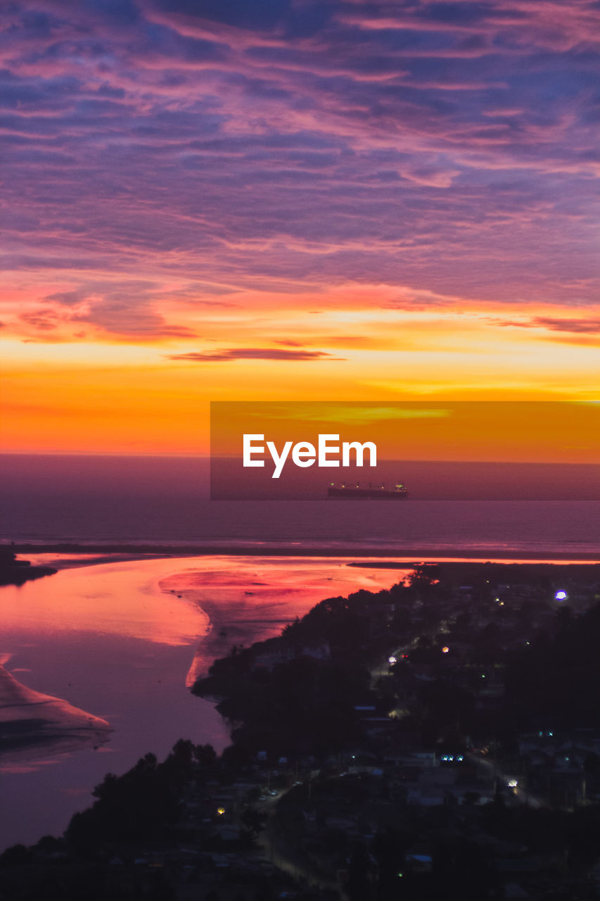 Scenic view of sea against dramatic sky during sunset