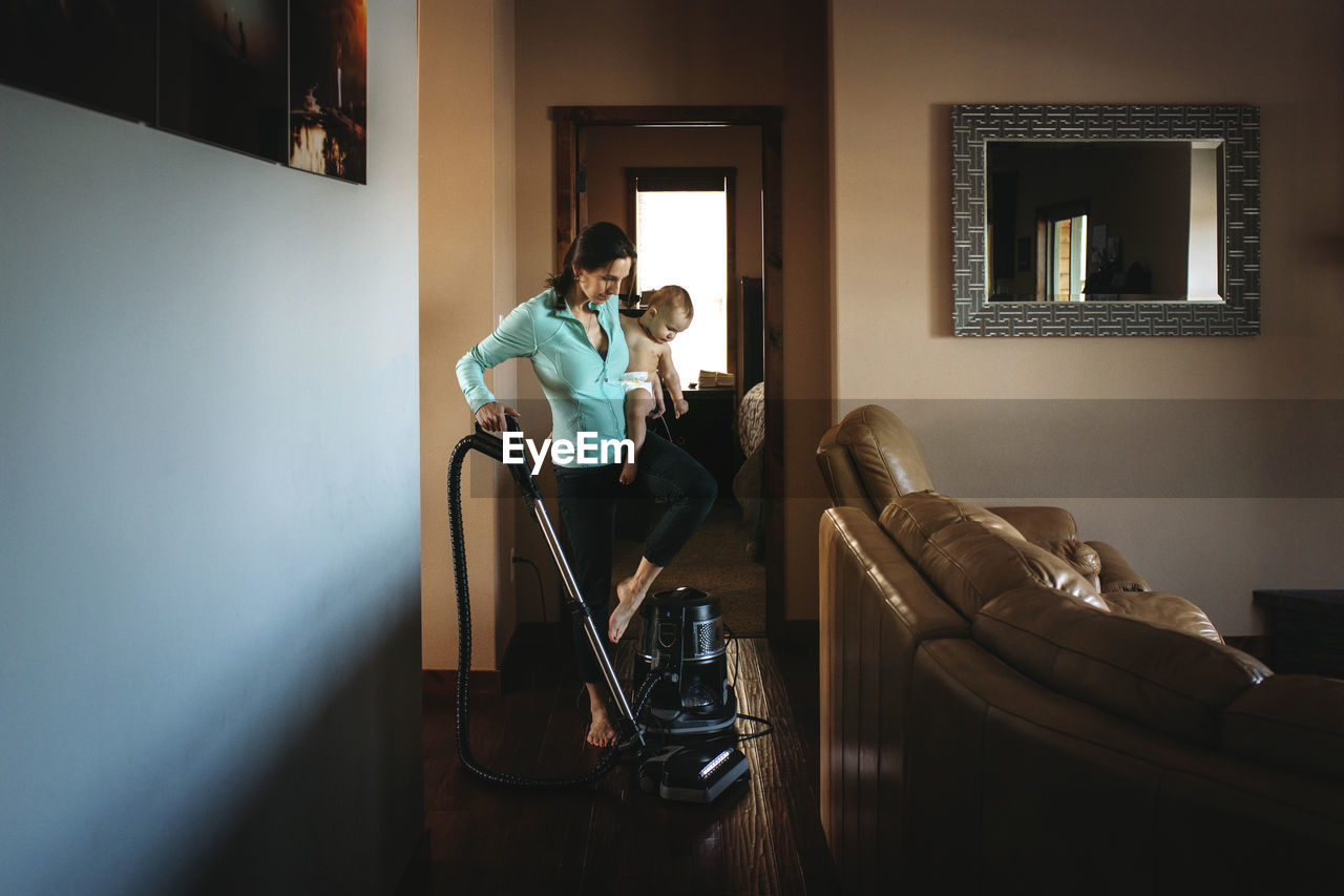 Mother carrying daughter while cleaning house