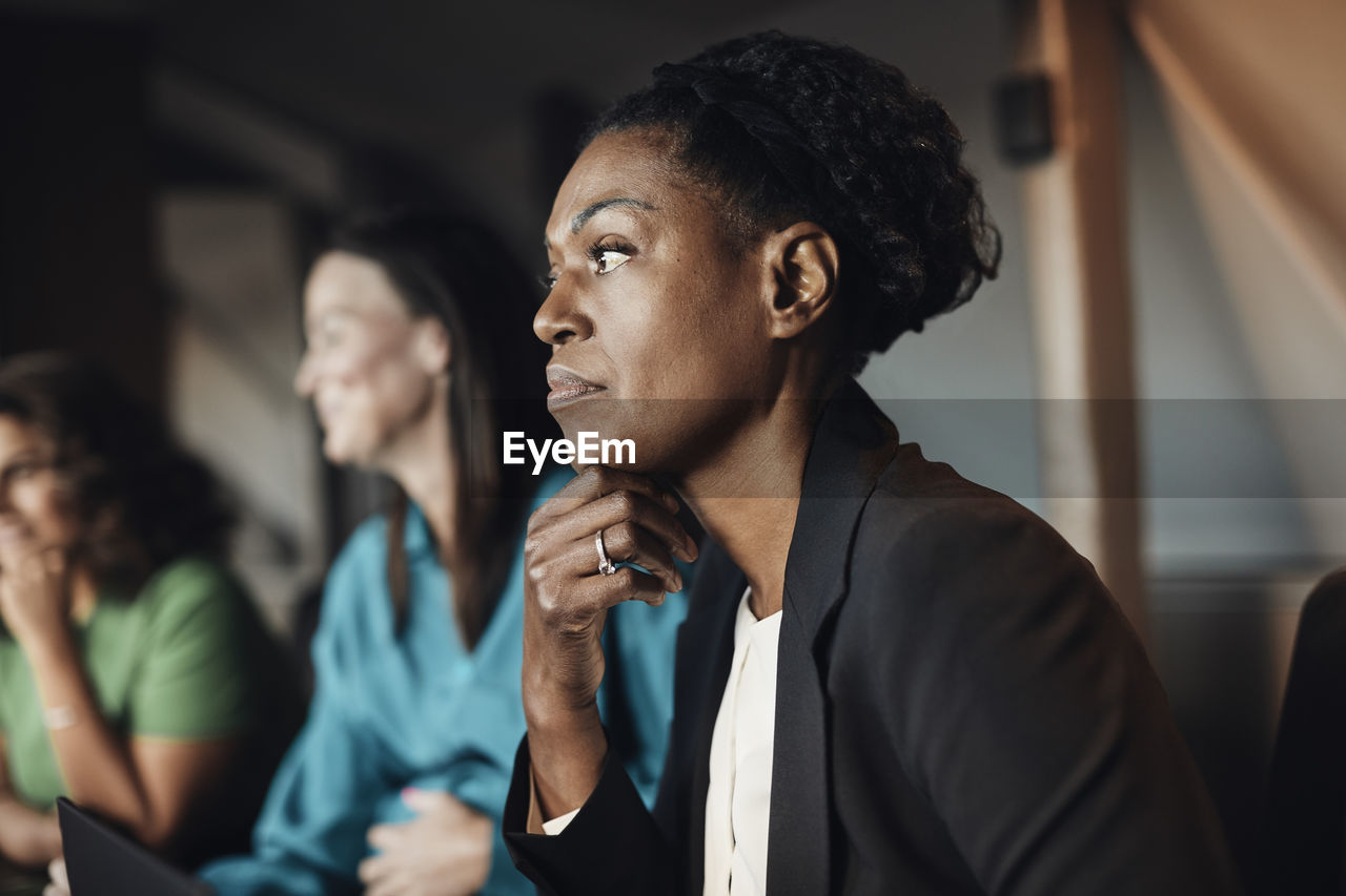 Thoughtful businesswoman with hand on chin during meeting at office