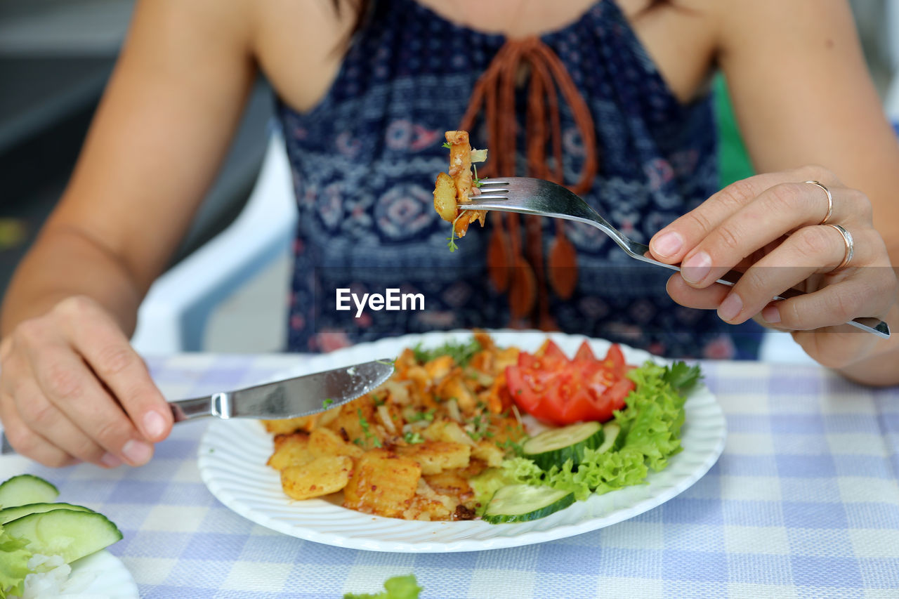 Midsection of woman eating food at table