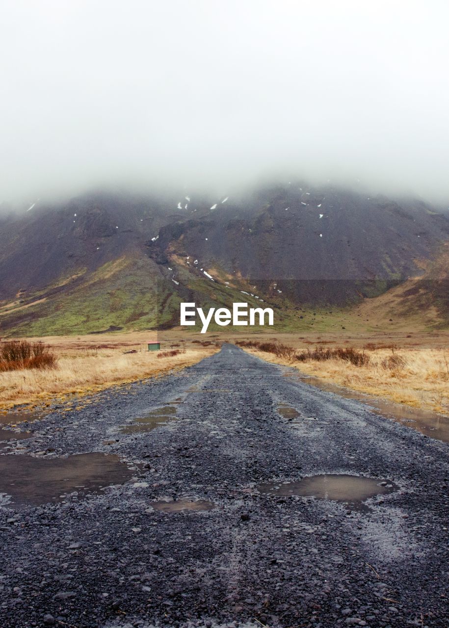 Road leading towards mountains against sky