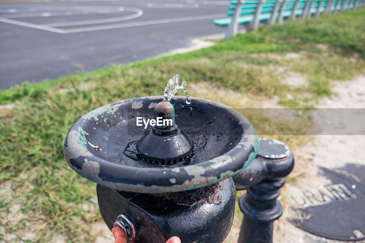 Cropped image of person pressing drinking fountain