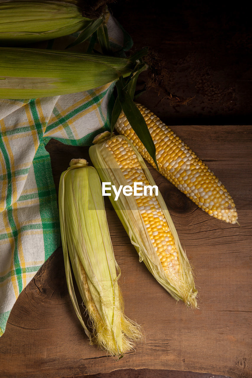 food, food and drink, yellow, healthy eating, vegetable, corn, sweet corn, wellbeing, freshness, no people, green, wood, crop, indoors, leaf, still life, agriculture, corn kernels, cereal plant, organic, high angle view, produce, studio shot, rustic, raw food, plant, table, nature, close-up