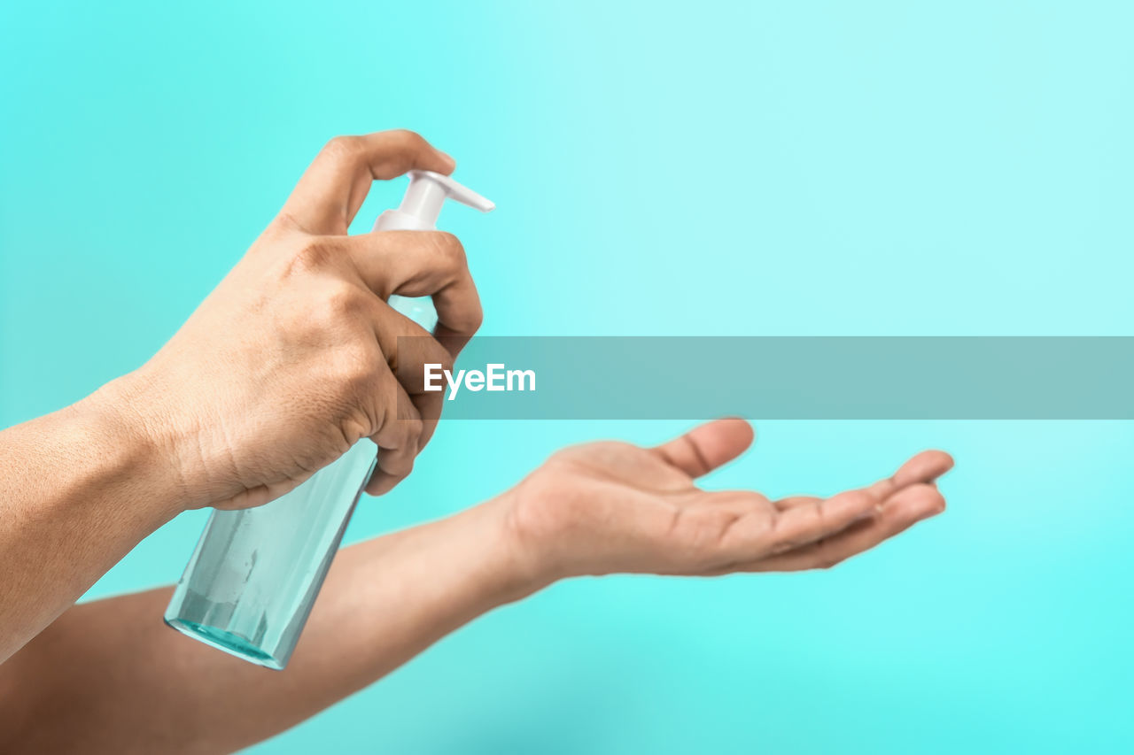 CLOSE-UP OF HAND HOLDING EYEGLASSES AGAINST WHITE BACKGROUND