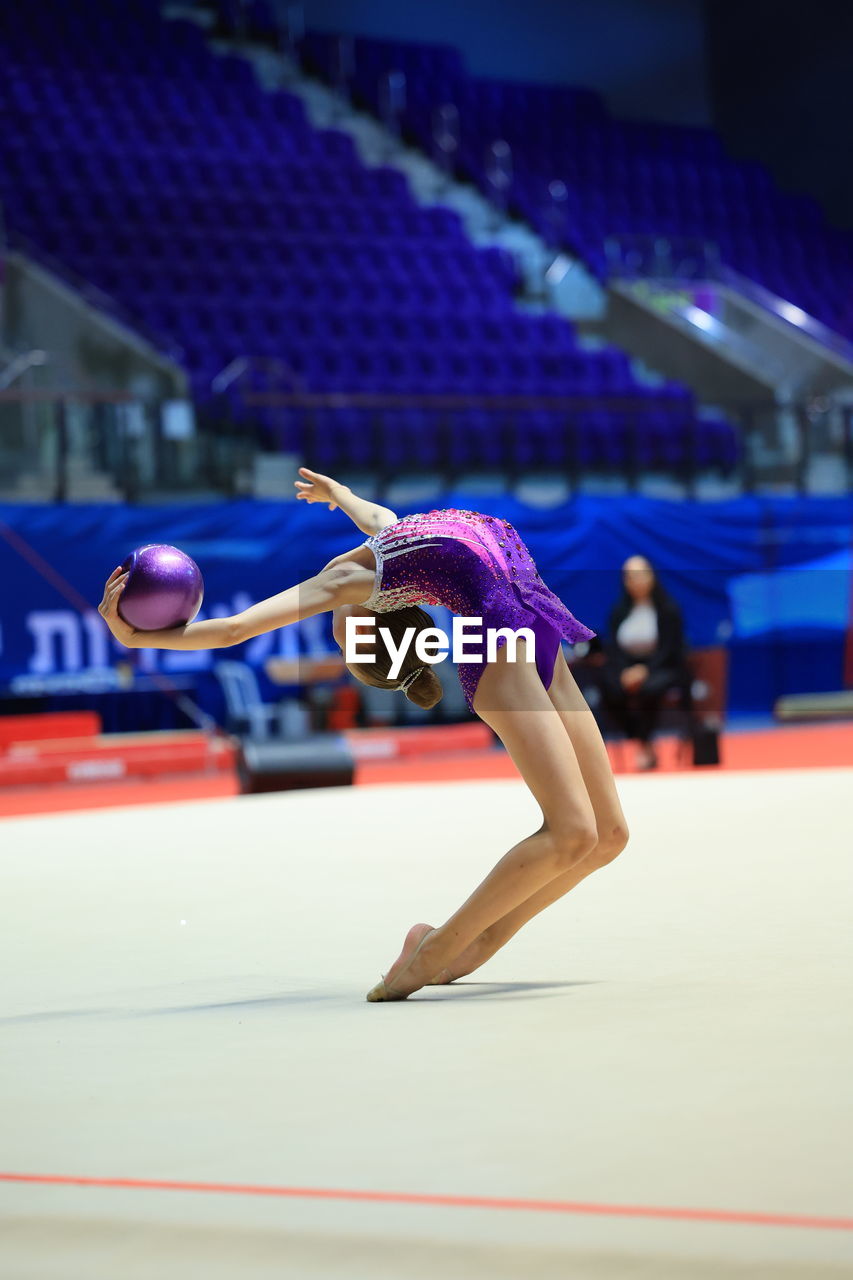 Girl gymnast performs an exercise with a ball