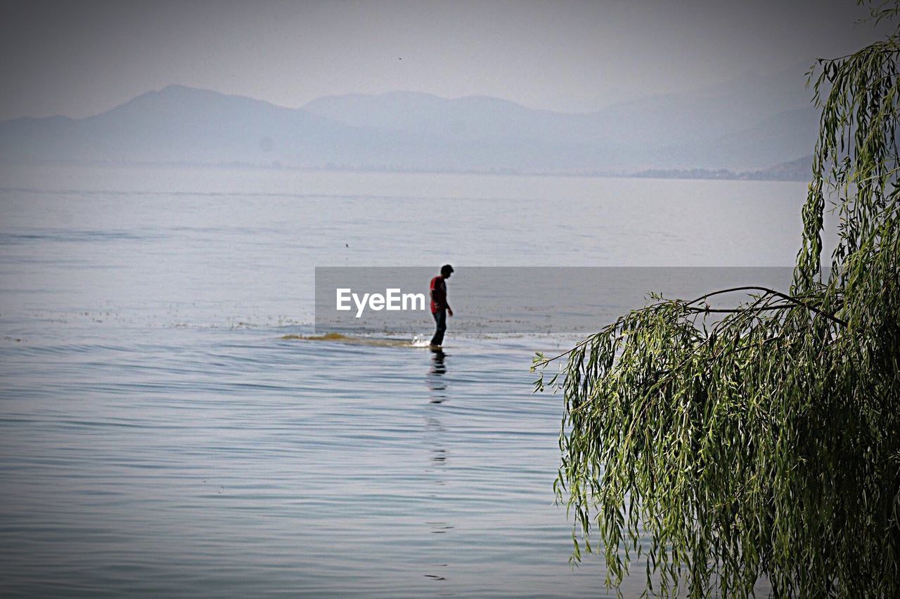 Man standing in lake against sky