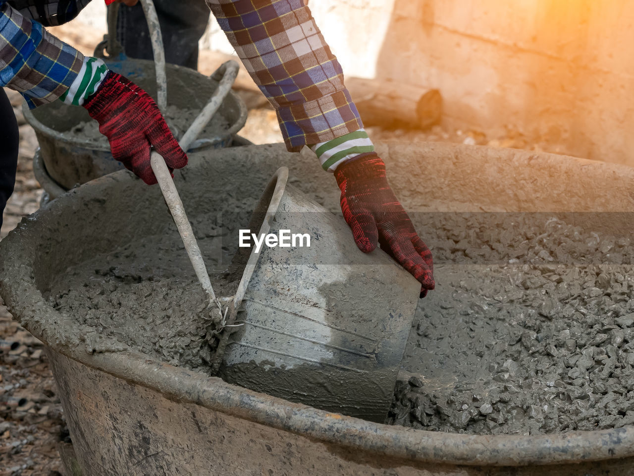 Man collecting cement in bucket while working at construction site