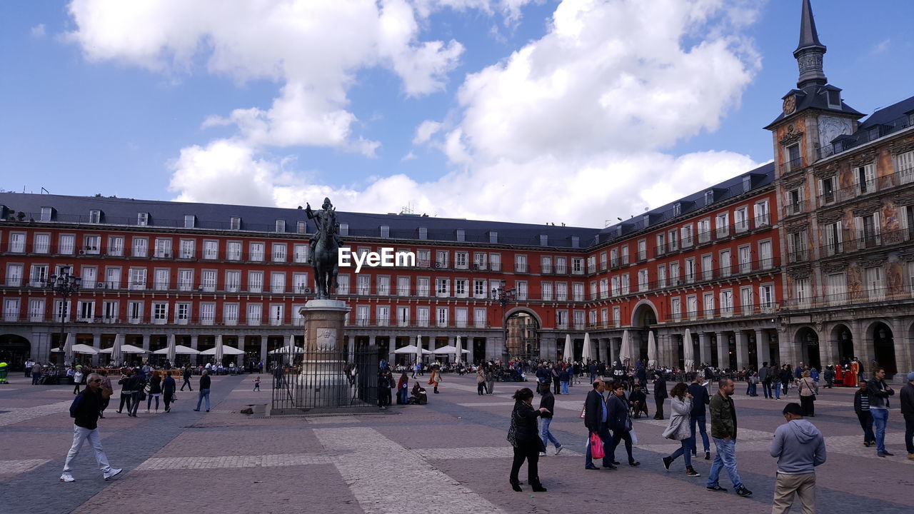 People walking at plaza mayor against sky in city