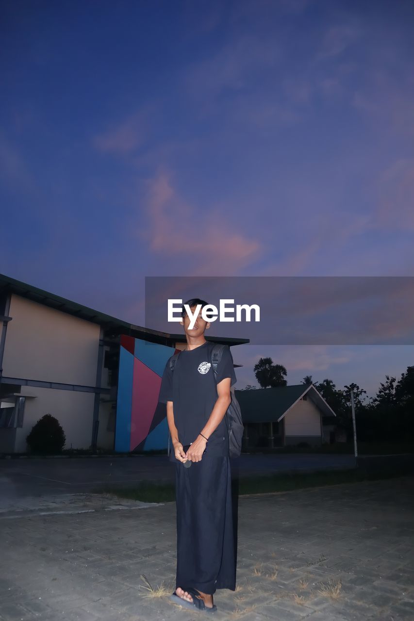 Portrait of young man standing against sky