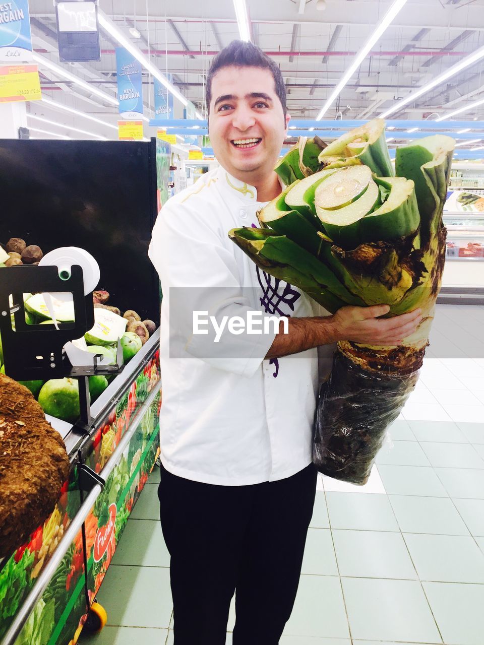 PORTRAIT OF SMILING YOUNG MAN STANDING IN STORE