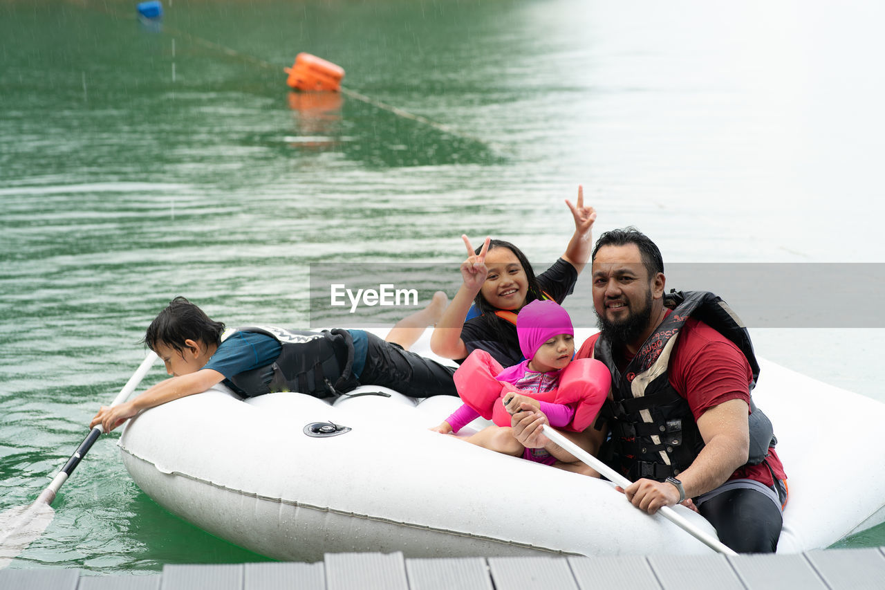 Father with children floating on inflatable ring over lake