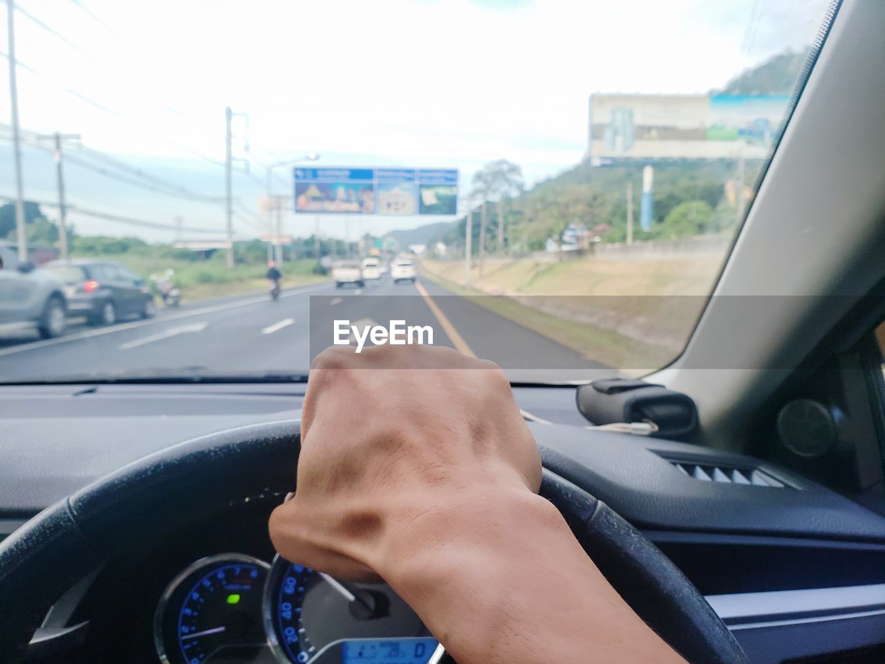Cropped image of person hand driving car on road