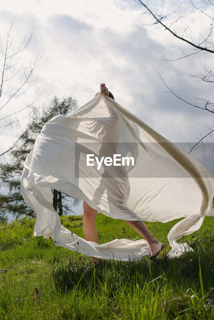 Lady spinning with white cloth in meadow scenic photography