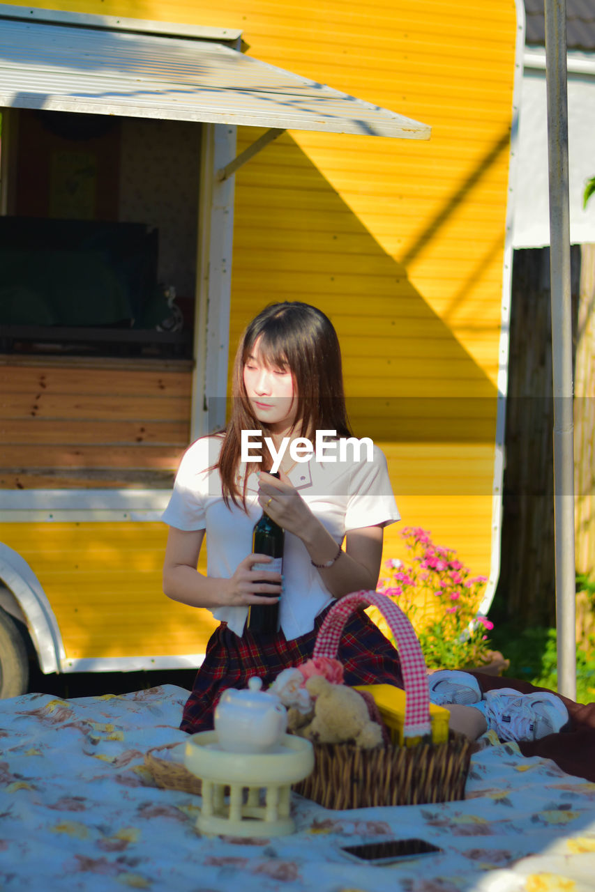 portrait of young woman sitting on table in yard