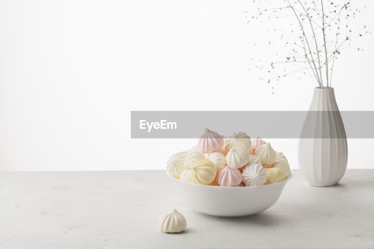 CLOSE-UP OF FRESH WHITE ROSES ON TABLE AGAINST GRAY BACKGROUND