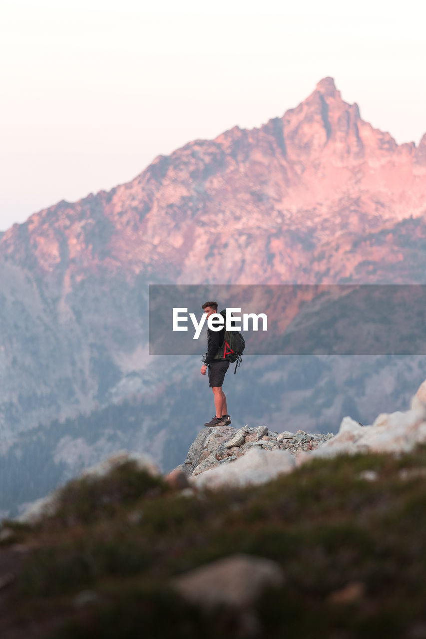 Full length of man standing on rock in mountains against sky