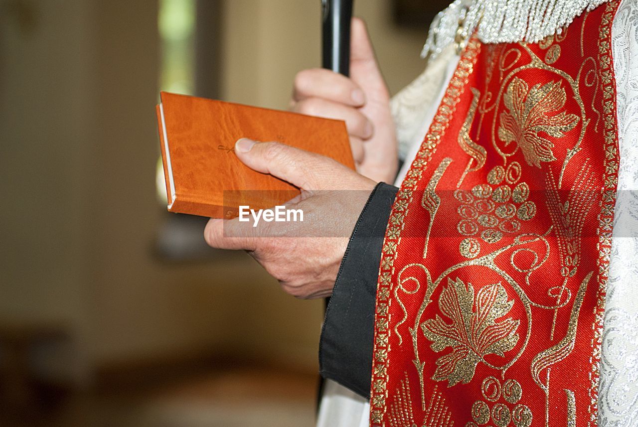 Midsection of priest holding bible in church