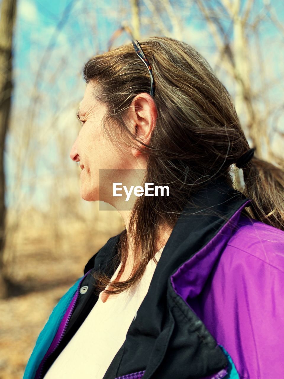 Side view of woman standing against trees