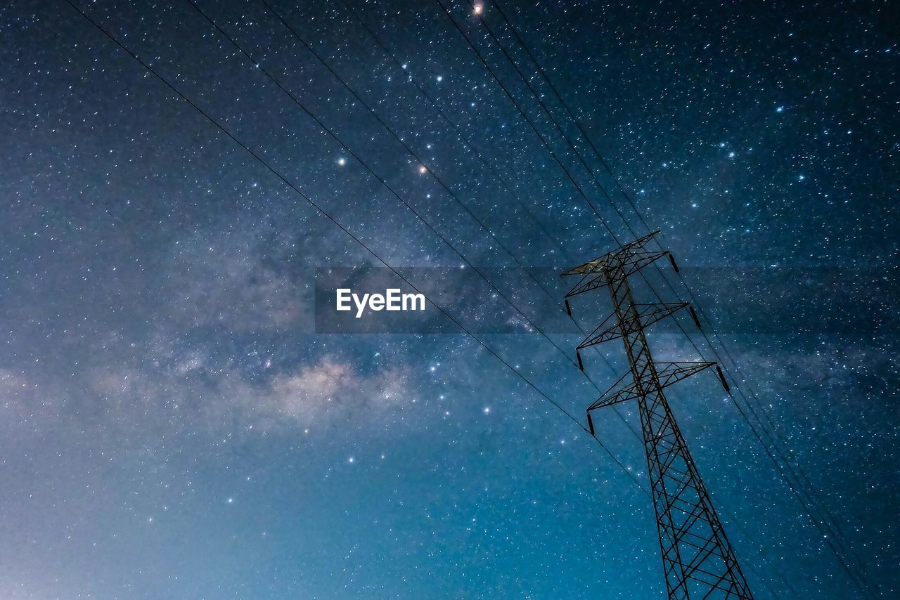 Low angle view of electricity pylon against star field