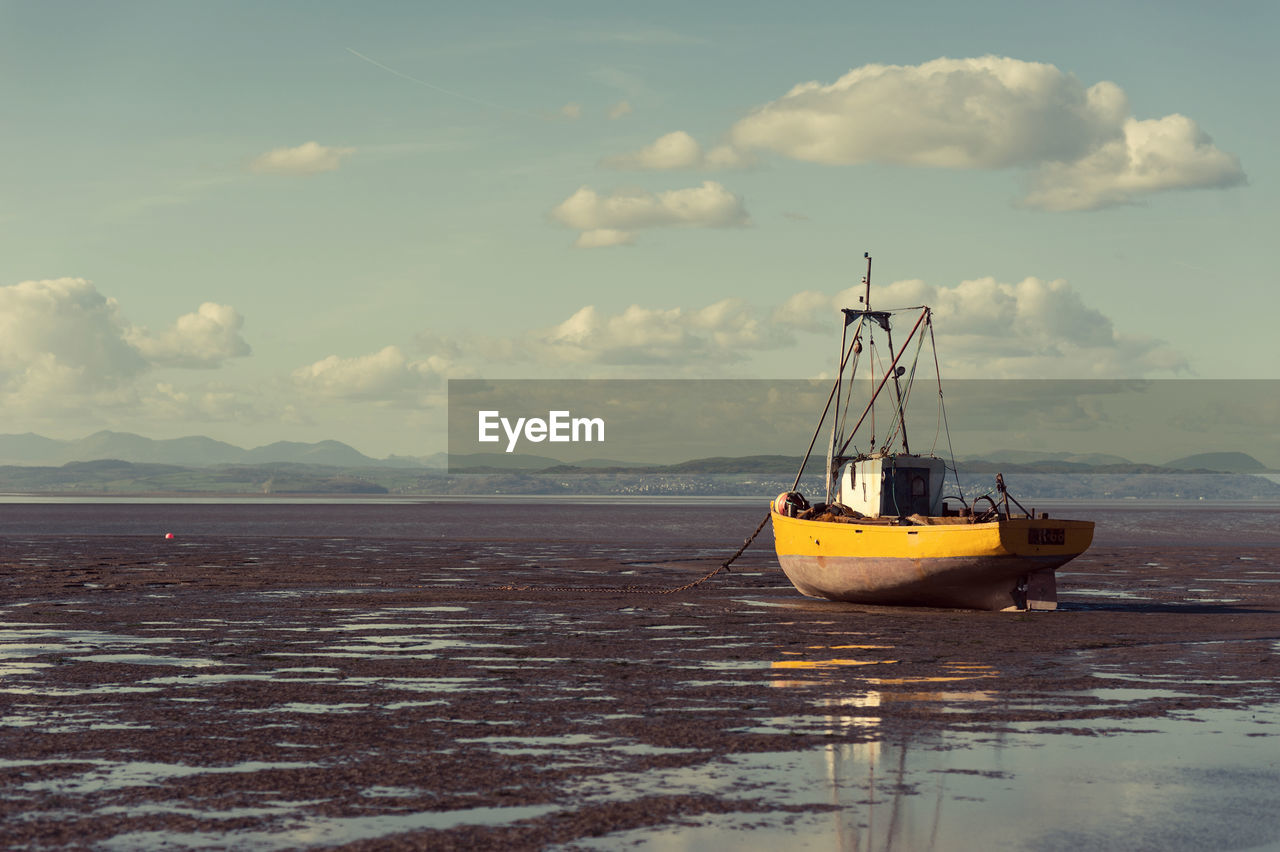 Boat moored at beach against sky