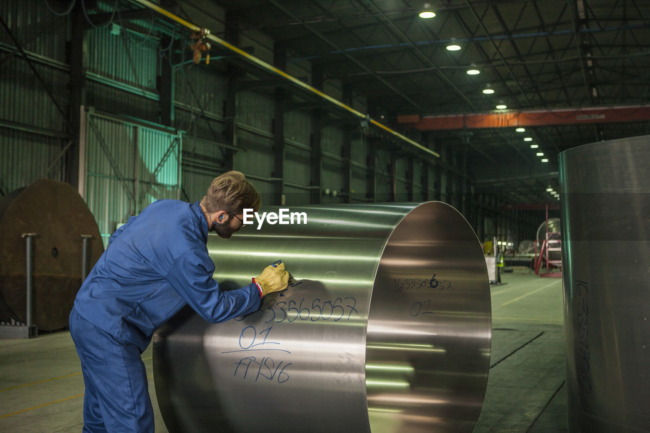 Worker labeling metal in factory