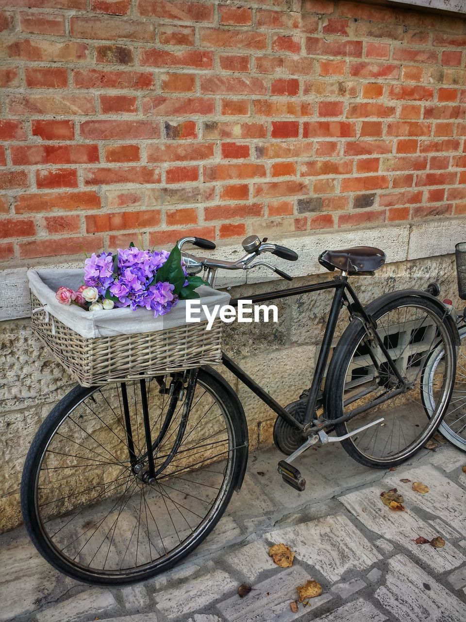 Bicycle with flowers in basket against brick wall