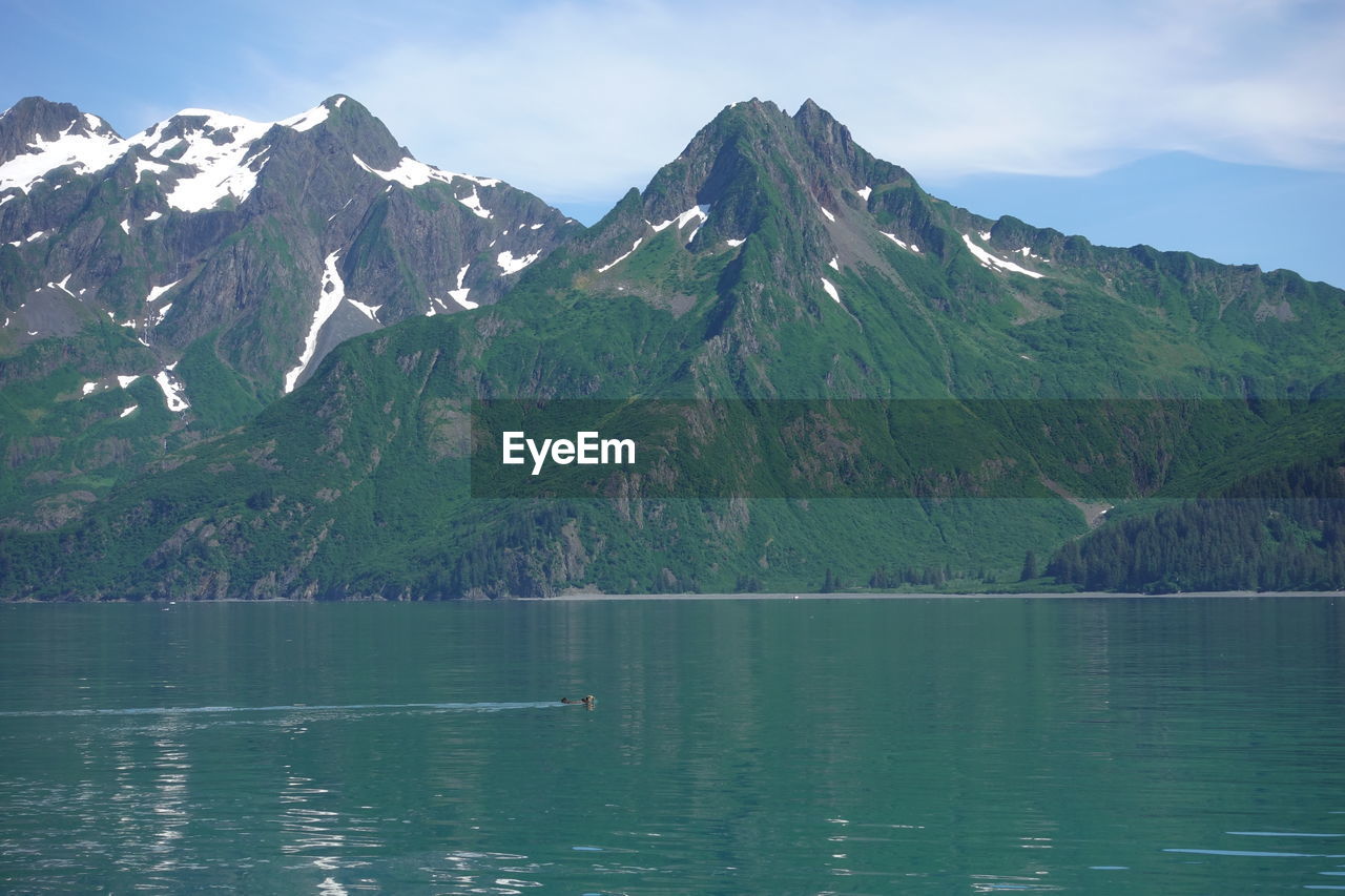 Scenic view of lake by mountains against sky