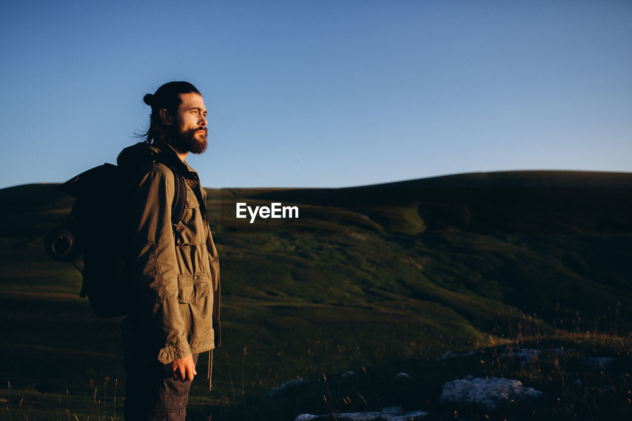 Man looking at mountains against clear sky