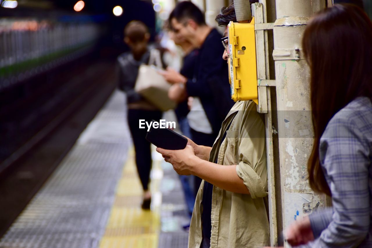 REAR VIEW OF WOMAN WITH UMBRELLA AT RAILROAD STATION