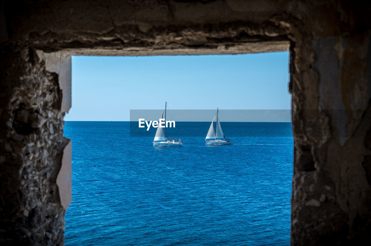 Sailboats sailing in sea against clear blue sky