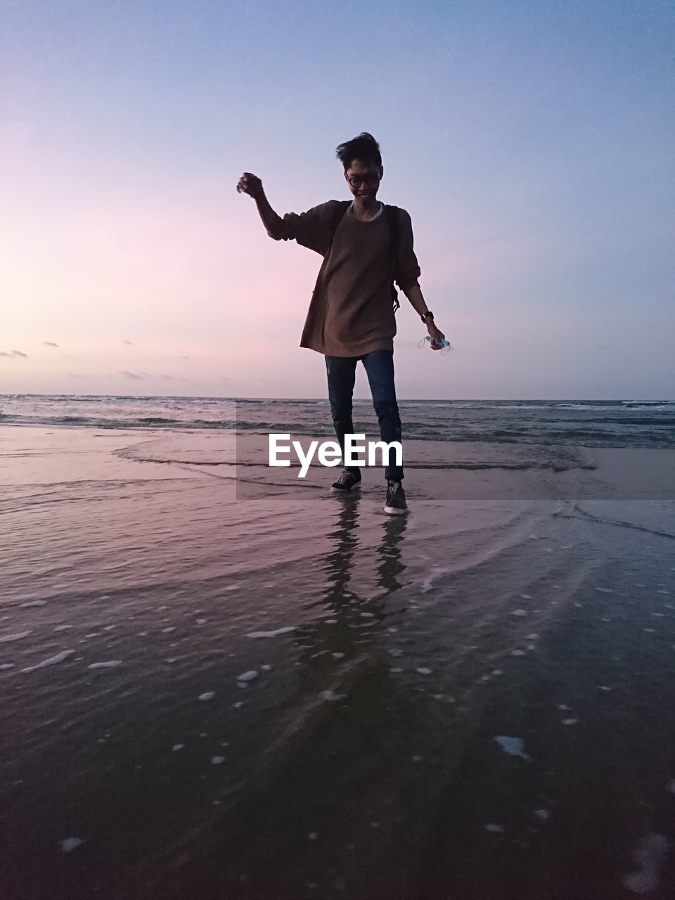 Full length of man standing on beach during sunset