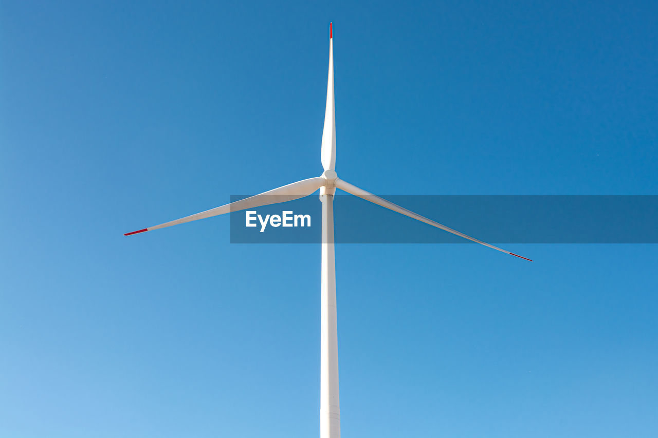 Low angle view of windmill against clear blue sky