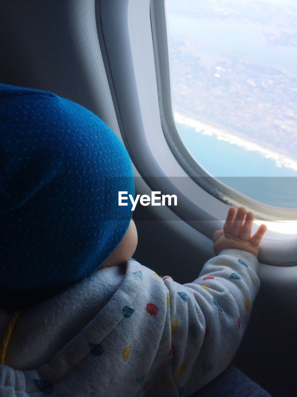 Close-up of baby boy looking through airplane window