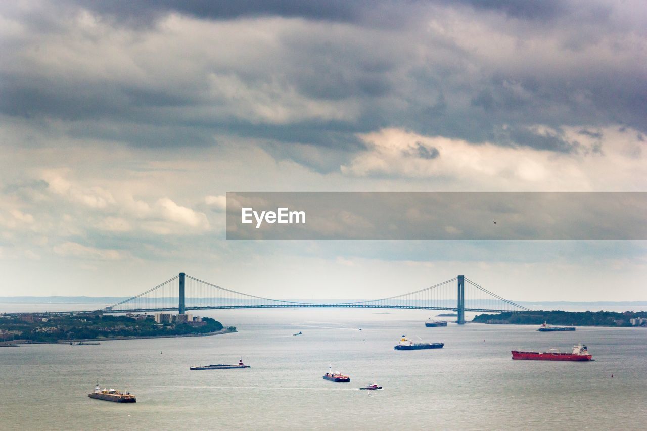 View of suspension bridge over sea against cloudy sky