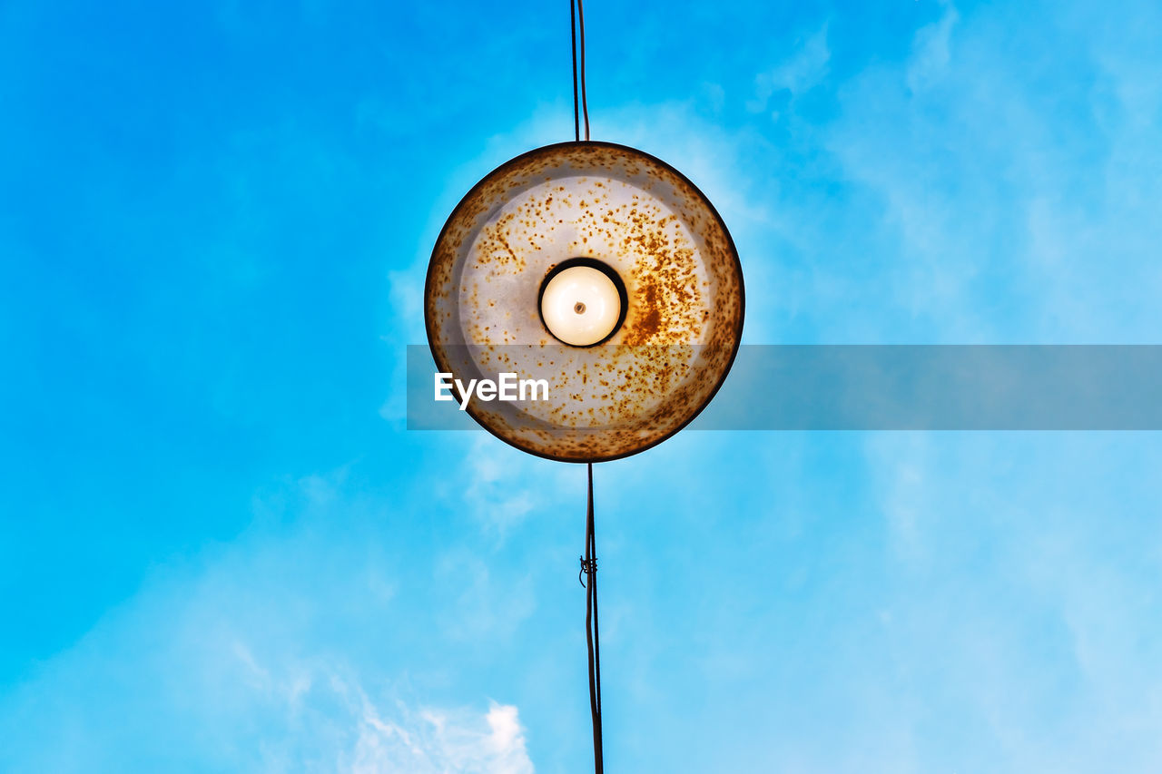 Low angle view of pendant light hanging against blue sky