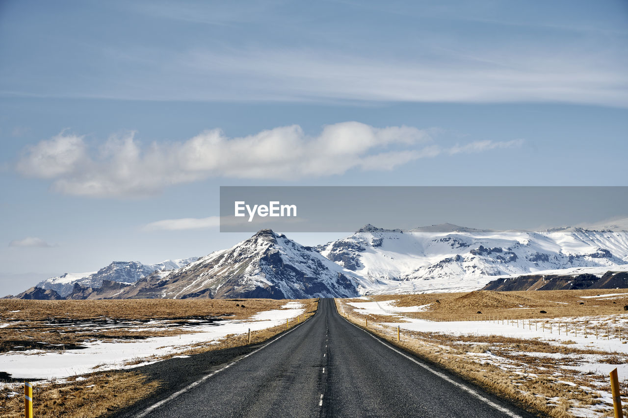 Empty road in terrain with snowy mountains