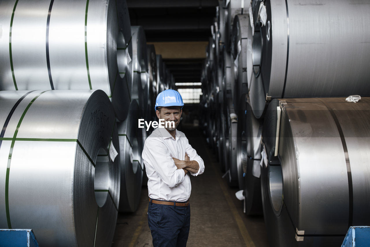 Smiling man with arms crossed standing in industry