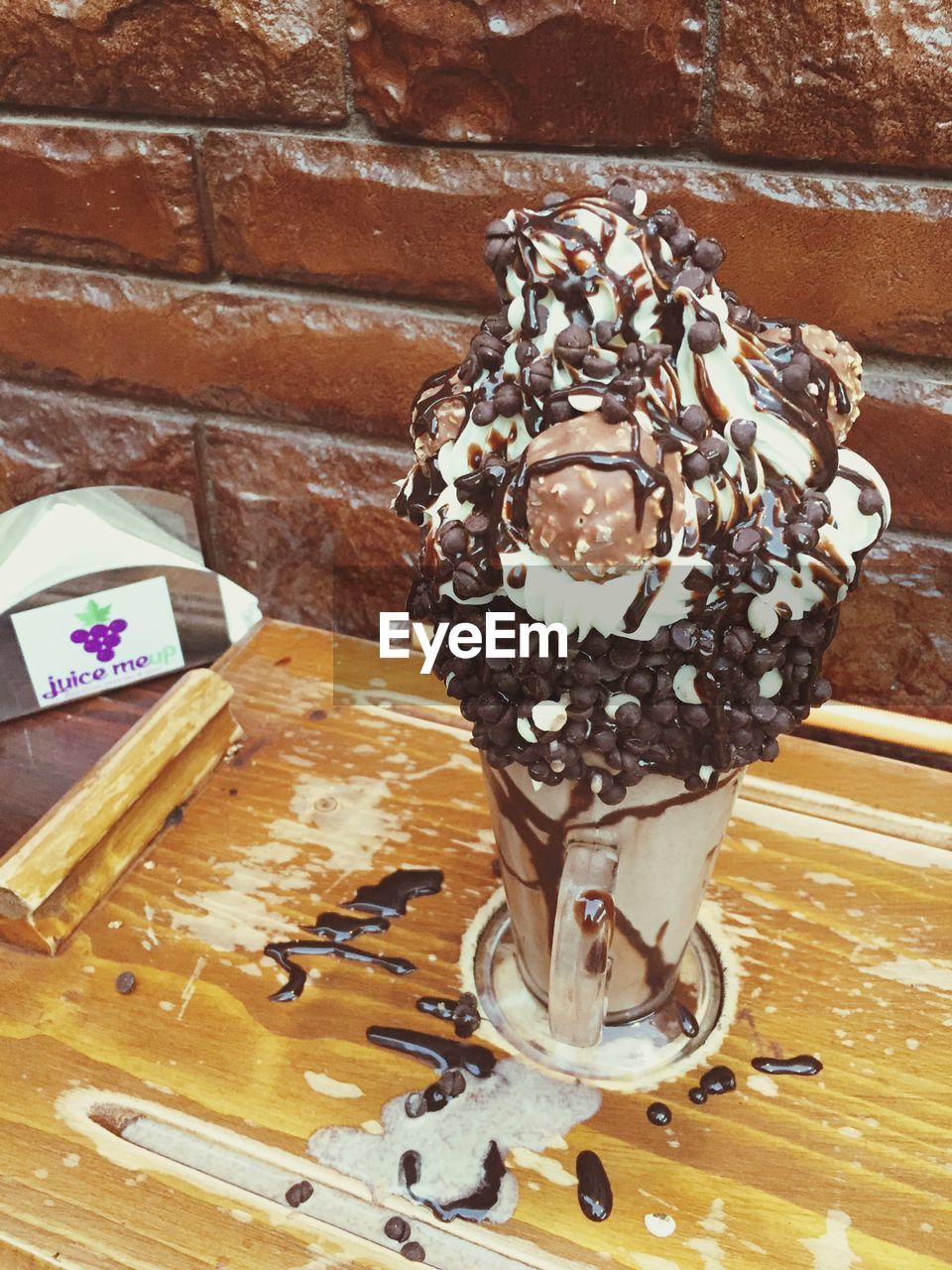 CLOSE-UP OF ICE CREAM ON TABLE AGAINST BRICK WALL