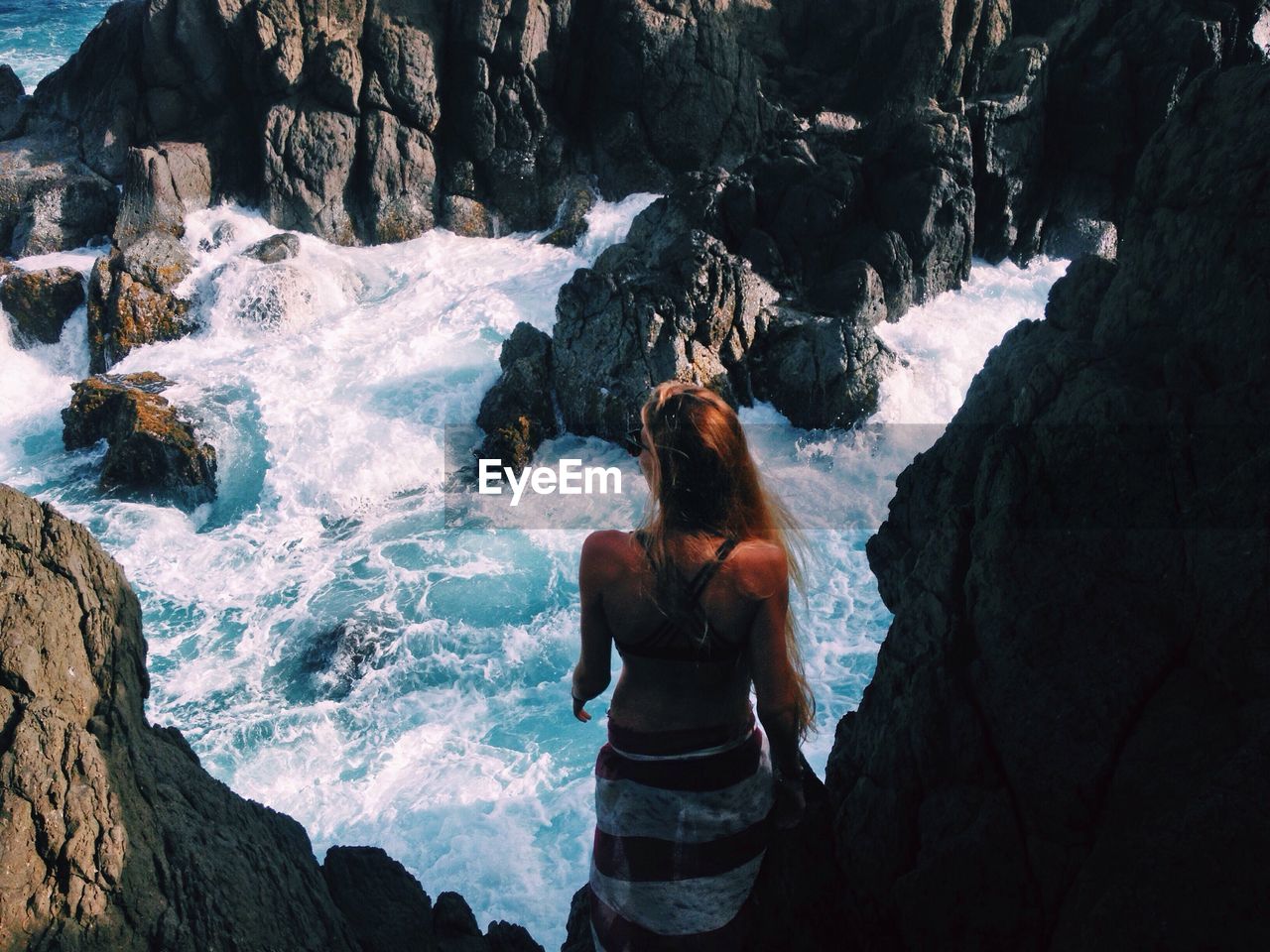 High angle rear view of woman standing by river on sunny day