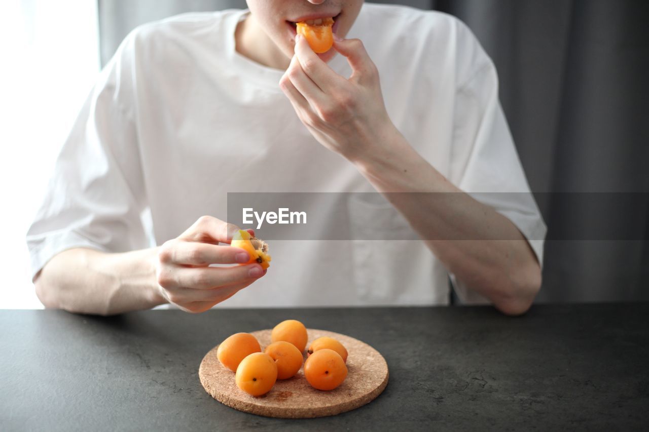 MIDSECTION OF MAN PREPARING ORANGE