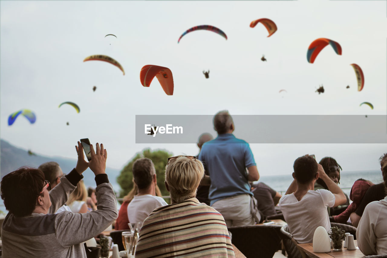 REAR VIEW OF PEOPLE FLYING OVER THE SKY