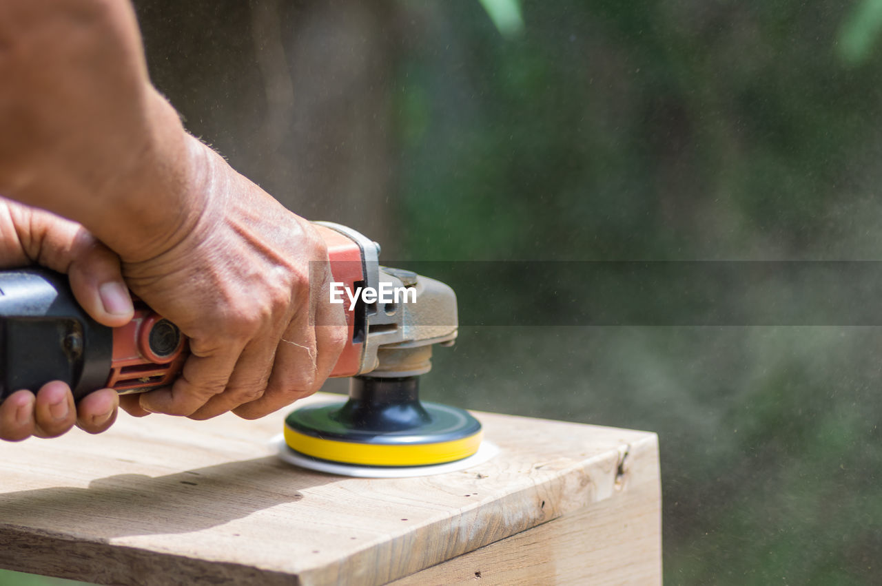 Cropped hands of person using work tool on wood