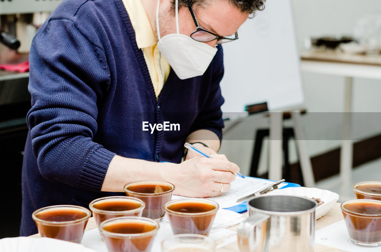 Midsection of man writing on document at cafe