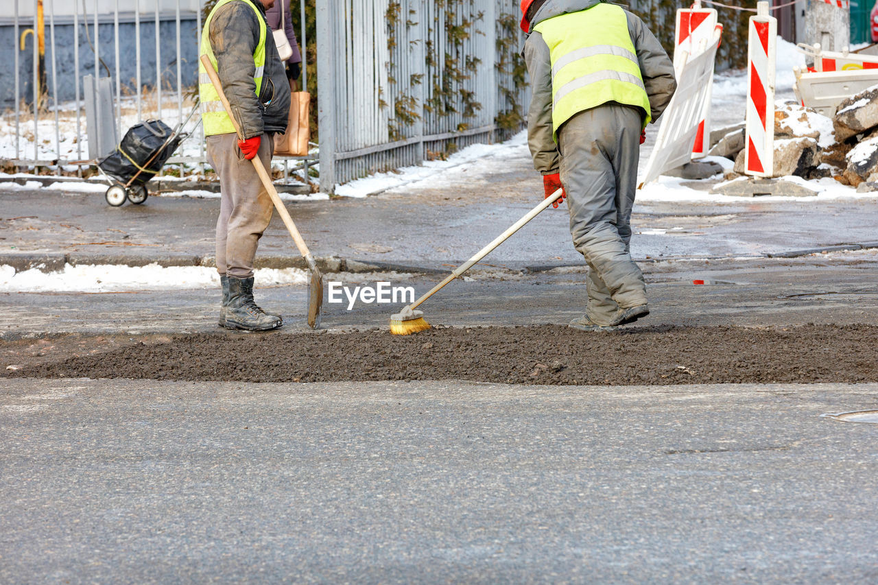 A construction team is patching up the pavement of the carriageway.