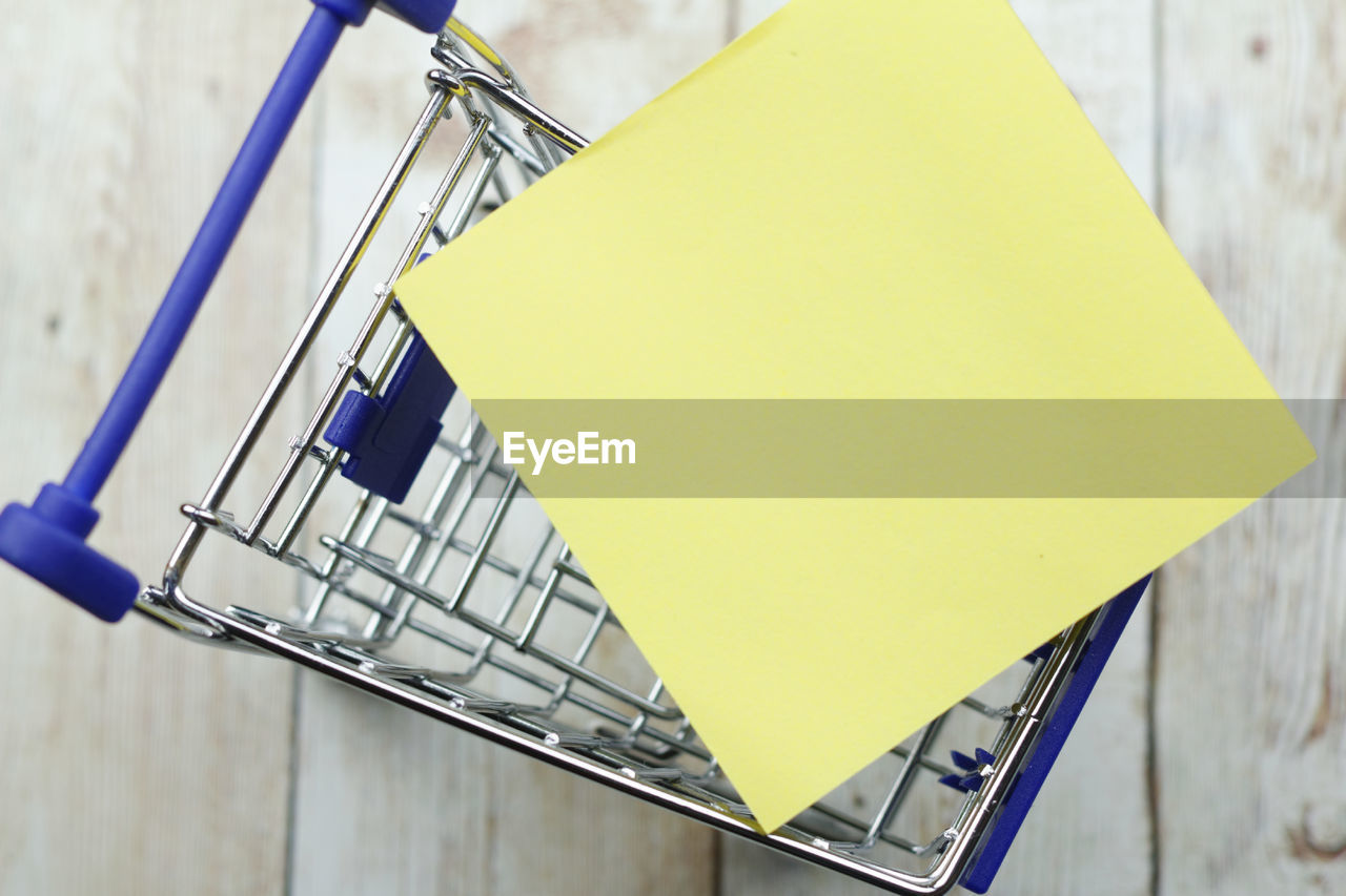 Directly above shot of small shopping cart and adhesive note on table