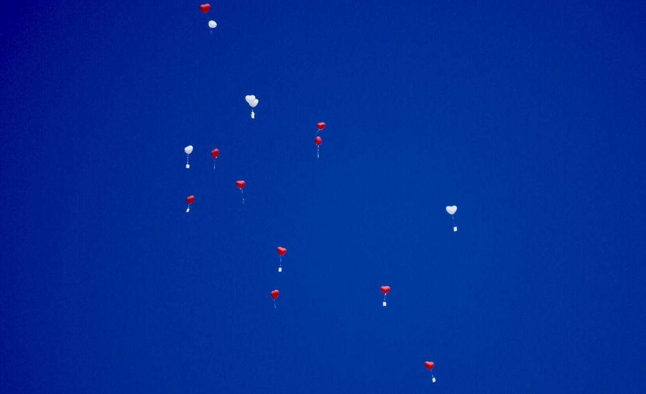 LOW ANGLE VIEW OF BALLOONS FLYING AGAINST BLUE SKY